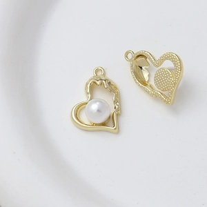 Detailed close-up of a heart-shaped gold pendant with a white pearl inlay on white background