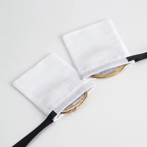Detail of gold V-shaped crystal bracelets with white linen drawstring jewelry pouches