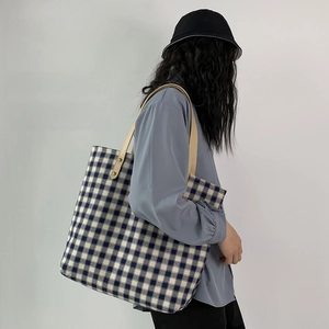 Detail der blau-weiß karierten Canvas-Tragetasche mit beigen Ledergriffen für Damen