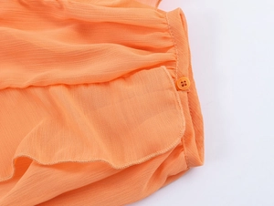Detail of orange chiffon shirt featuring textured crepe fabric and matching resin button