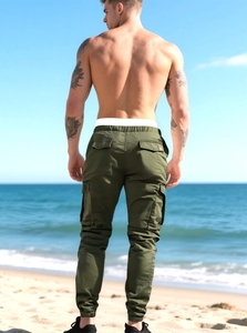 Outdoor view of men's olive cargo pants with multiple pockets and tapered cuffs