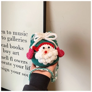 Detail of handmade crochet Christmas Santa bag with green knit pattern and red pom poms