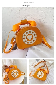 Detail view of orange retro telephone shoulder bag with handset handle and rotary dial