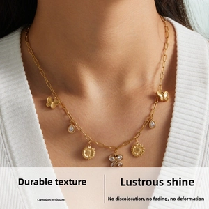 Close-up of gold butterfly and sunflower charms on a teardrop zircon necklace set