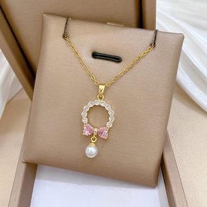 Detail of gold necklace pendant with pink bow zircon and elegant white pearl drop