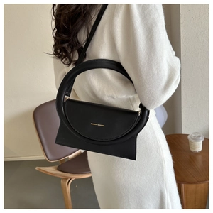 Detail einer minimalistischen schwarzen Ledertasche mit Rundgriff und goldenem Schriftzug