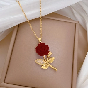 Detail of red velvet rose pendant with crystal leaves on a gold necklace chain
