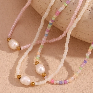 Detail of colorful freshwater pearl necklaces with gold beads on a textured background