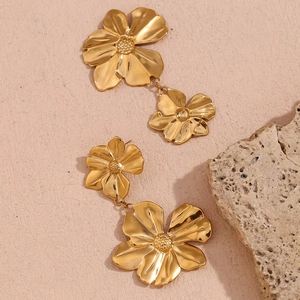 Detailed close-up of 18K gold-plated double floral earrings on a textured stone base