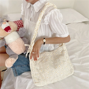 Daisy floral pattern on off-white canvas shoulder bag worn in a casual lifestyle setting