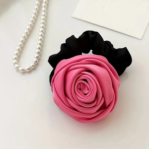 Detail of pink satin rose hair tie with smooth silk texture and black elastic scrunchie