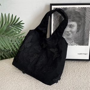 Close-up of black canvas tote bag featuring 3D butterfly embroidery and mesh lace overlay