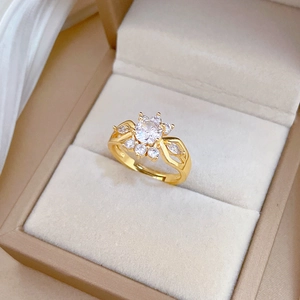 Macro detail of gold adjustable ring featuring a round zircon and crown shaped petals