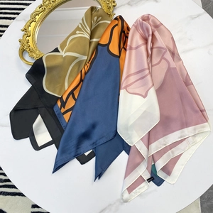 Elegant floral print satin silk scarves displayed on white marble tabletop with vintage mirror
