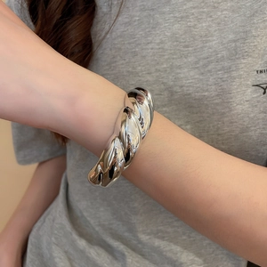 Close-up of silver irregular twisted cuff bracelet with thick metallic texture for women