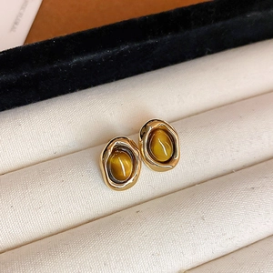 Close-up detail of retro geometric gold earrings with amber tiger eye stones in jewelry box