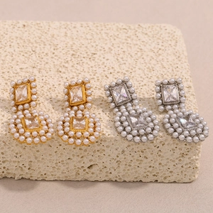 Detail of luxury gold and silver earrings with zircon and pearls on stone base