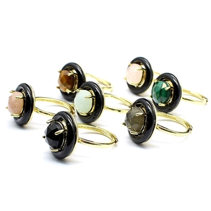 Detailed macro view of multiple gold-tone natural gemstone rings on white background