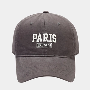 Close-up of white PARIS FRENCH embroidery on a dark grey cotton baseball cap texture