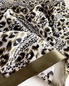 Detailed close-up of leopard print satin scarf showing fabric texture and green hem