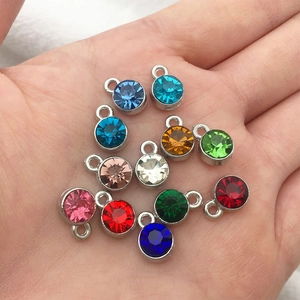 Close-up of colorful 7mm birthstone crystal pendants with silver metal settings in palm
