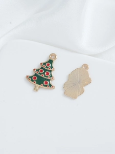 Detailed macro view of green enamel Christmas tree charms with red dots and golden metal backing