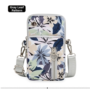 Detail of grey floral print phone bag with heart zippers and adjustable strap