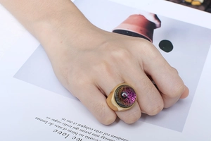 Close-up of a gold stainless steel ring with a large purple glass dome on a model hand