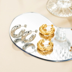 Detail view of bold twisted hoop earrings in polished gold and silver finish