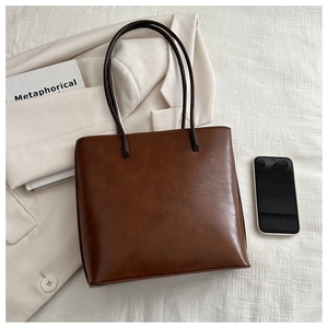 Close-up of brown leather tote bag styled with a white blazer for a chic commuting look