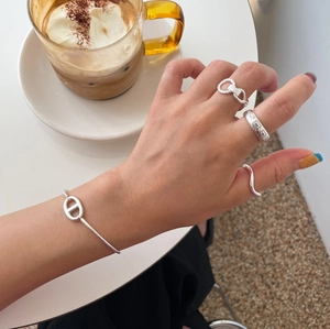 Close-up of 925 sterling silver woven twist rings and chain link bracelet on hand