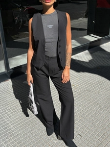 Detailed outdoor shot of a black vest and high-waist trousers with a printed grey top