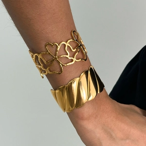 Close-up of gold stainless steel cuff bracelets with hollow floral and textured designs