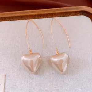 Boucles d'oreilles cœur perle élégantes avec crochets dorés sur fond en tissu doux