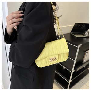 Close-up of lemon yellow quilted crossbody bag with gold chain and metal swivel lock