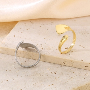 Detailed view of silver and gold irregular serpent style open rings on a stone display