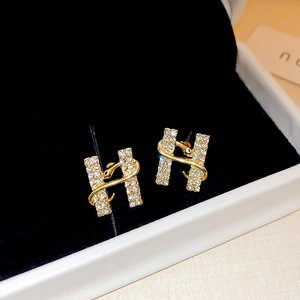 Macro detail of H-shaped earring with crystal snake wrap in gold finish