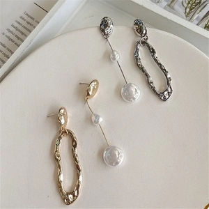 Detail of geometric Baroque pearl drop earrings in gold and silver asymmetric metal designs