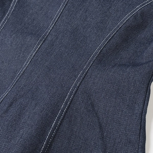 Détail du tissu denim bleu foncé avec des coutures blanches contrastées de précision