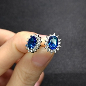 Close-up of sapphire blue crystal earrings with diamond halo and silver metal base