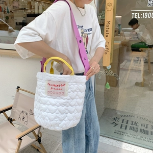 Détail du sac seau matelassé blanc à motif cœur et bandoulière violette sur modèle