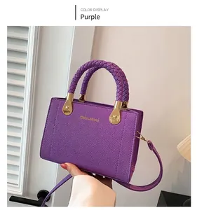 Détail d'un sac violet en cuir grainé avec poignées tressées et finitions dorées chic