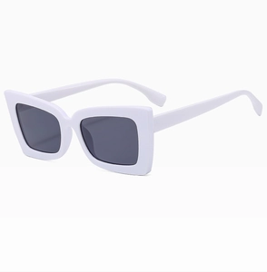 Detail view of square white sunglasses with thick frames and dark lenses at a 45-degree angle