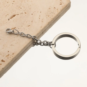 Polished silver stainless steel key ring with chain and lobster clasp on stone base