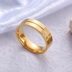Minimalist gold titanium steel ring with central groove detail on stone background