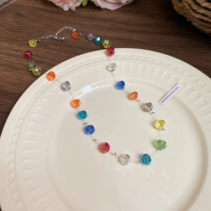 Detail of colorful crystal beaded necklace with metal clasp on white ceramic plate