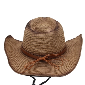 Detail of woven straw cowboy hat featuring brown leather band and adjustable wind rope