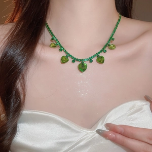Close-up of heart-shaped green zircon pendant on gold fringe necklace set