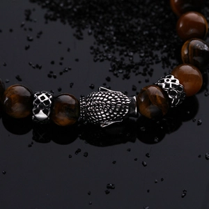 Detail shot of tiger eye beads with a vintage Buddha head on a dark stone background