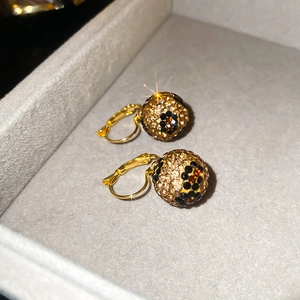 Macro detail of 18k gold plated sphere earrings with sparkling white and amber rhinestones